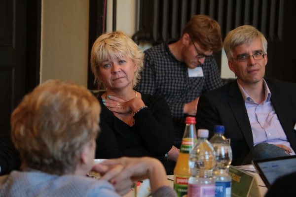 Cornelia Lüddemann und Olaf Meister sitzen an einem Tisch mit einer Bürgerin und hören dieser zu. 