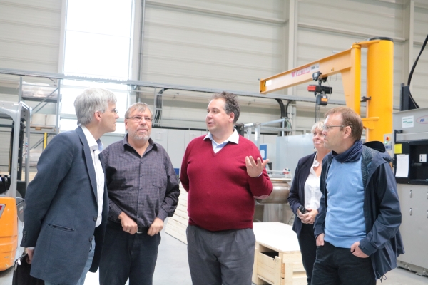 Olaf Meister diskutiert mit vier weiteren Personen in der Produktionshalle der Firma Almeco in Bernburg. 