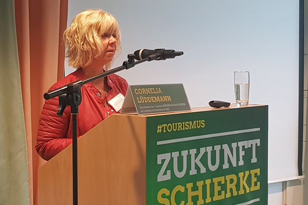 Cornelia Lüddemann bei ihrer Rede am Redepult. Ein Mikrofon steht neben dem Redepult. Auf dem Redepult liegt eine Fernbedienung sowie stehen dort ein Wasserglas und ein Namensschild.